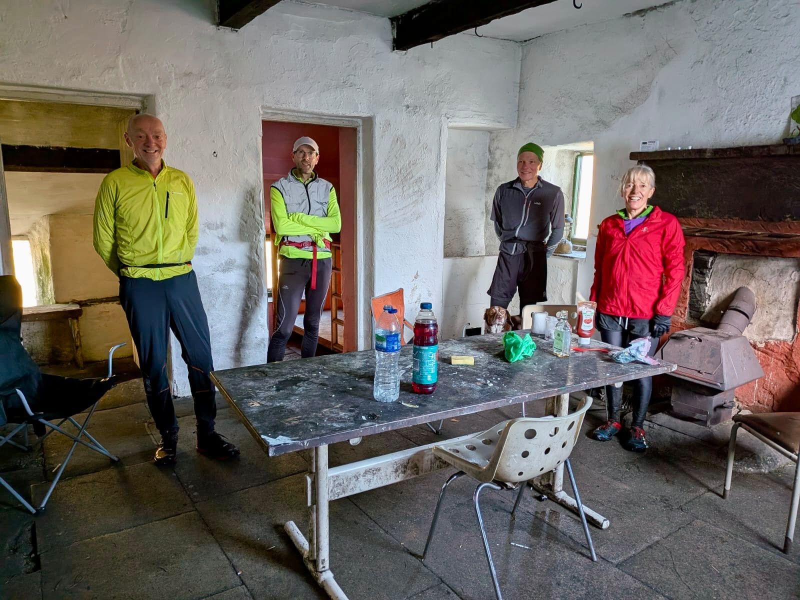 Runners inside a whitewashed bothy with a table and an old range.