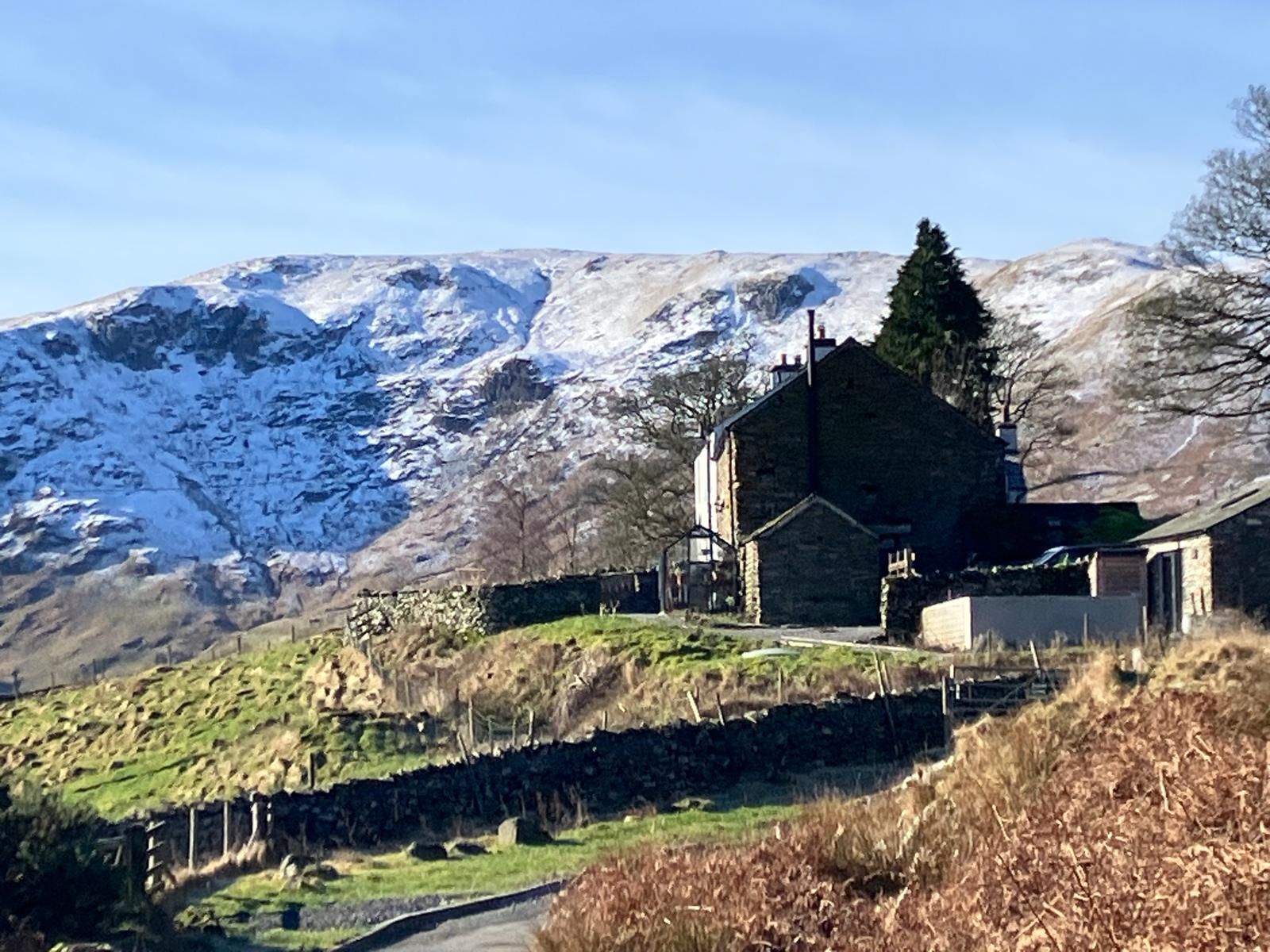 Truss Gap House, a stone farmhouse behind dry stone walls, with snow on the fell above.