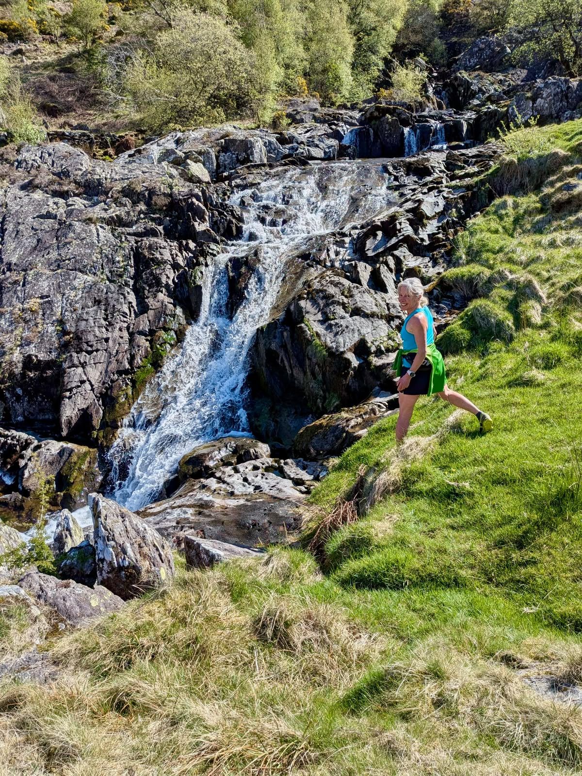 A runner climbs beside a rocky waterfall.